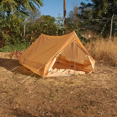 A small ridge-shaped pup tent stands at a campsite.
