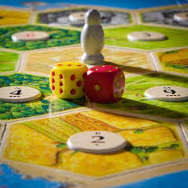 Two dice beside the numbered terrain hexes of a Catan game board.
