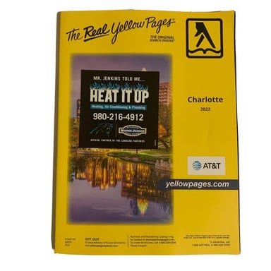 A printed business phone directory shown alongside a phone displaying digital listings.