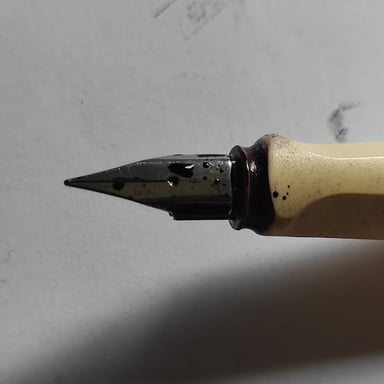 A pen leaking dark ink onto paper