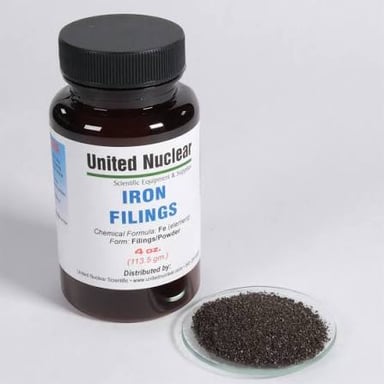 Dark iron filings lie beside a piece of steel.