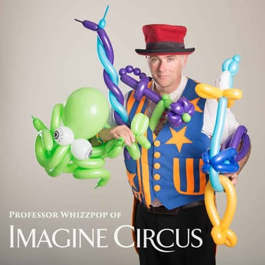 A circus performer juggling while making balloon animals