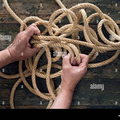 Hands pulling apart a knot in a rope