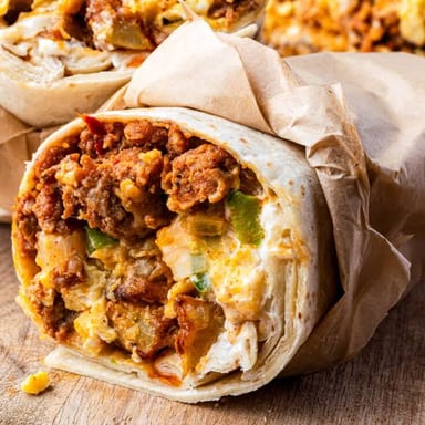 A burrito wrapped in a soft tortilla, with its filling visible at the cut end.