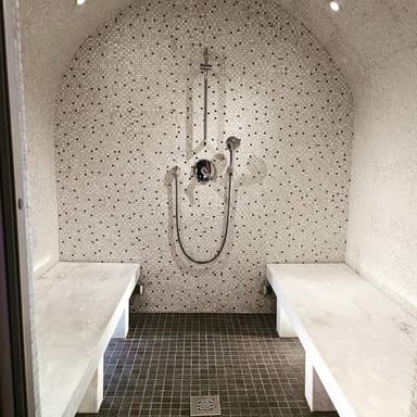 A tiled steam room with built-in benches and misty air.