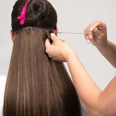 A stylist installing a hair weave extension.