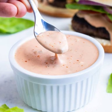 A chef presenting a small bowl of sauce as a special recipe ingredient.