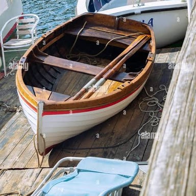 A wooden oar rests beside a small boat.