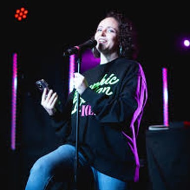 A spoken-word poet performing at a microphone before an audience.