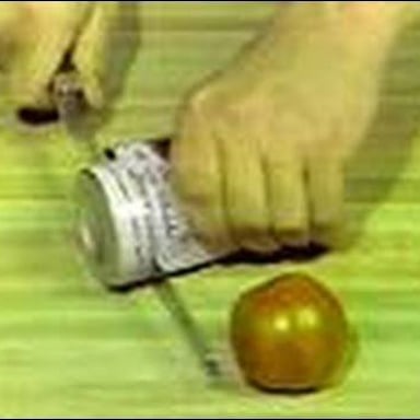 A Ginsu-style kitchen knife shown beside a tin can and sliced tomato.
