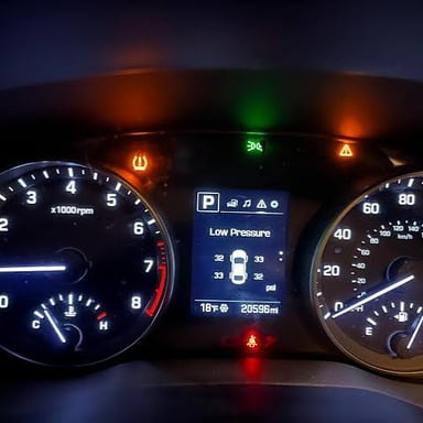 A car dashboard displaying a low tire pressure warning.