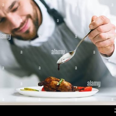 A chef pouring sauce over a plated dish.