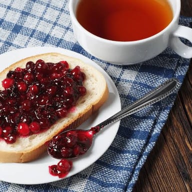 A cup of tea served with bread and jam.