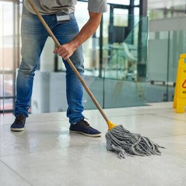 A person cleaning a floor with a mop.