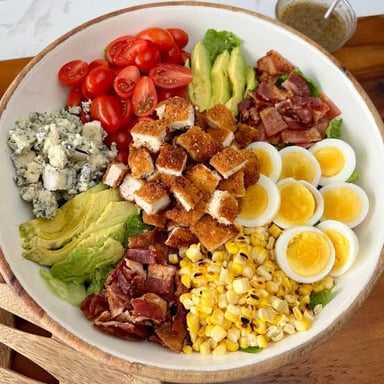 A Cobb salad topped with bacon, eggs, avocado, tomato, and blue cheese.