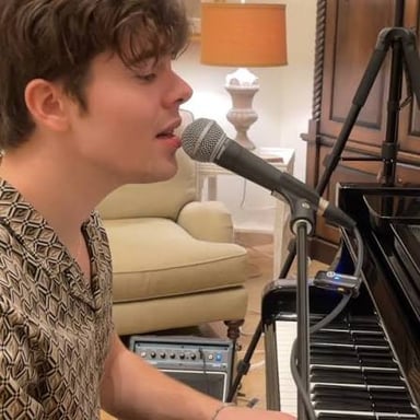 A musician plays a synthesizer in a calm, atmospheric setting.