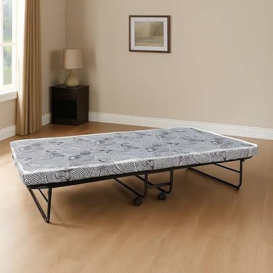 A portable folding cot set up beside a bed in a guest room.
