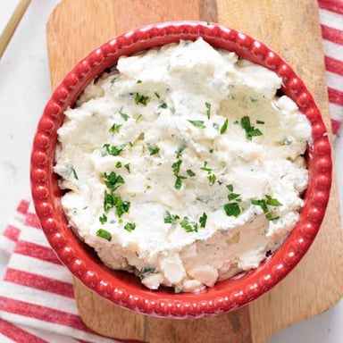 A bowl of soft ricotta cheese next to a slice of lasagna.