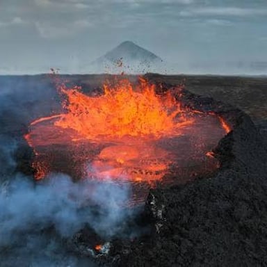 A glowing flow of molten lava moving over the ground.