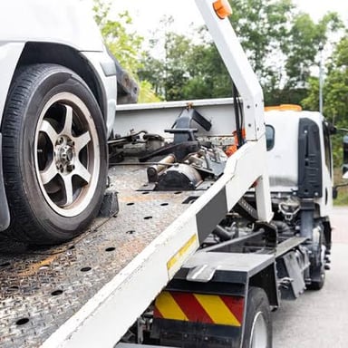 A tow truck transporting a car on its flatbed.