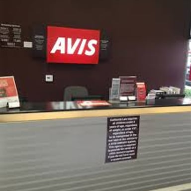 An Avis sign at a car-rental counter.