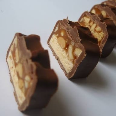 A cross-section of a Snickers bar showing its caramel layer alongside nougat and peanuts.