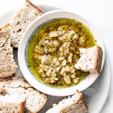 A bowl of pale aioli, a thick garlic sauce, served with bread.