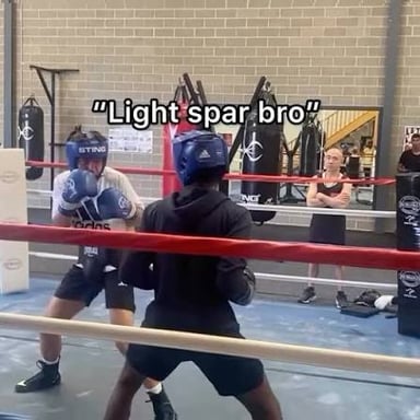 Two boxers practice controlled punches during a sparring session.