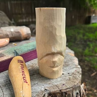 A person whittling a piece of wood with a knife