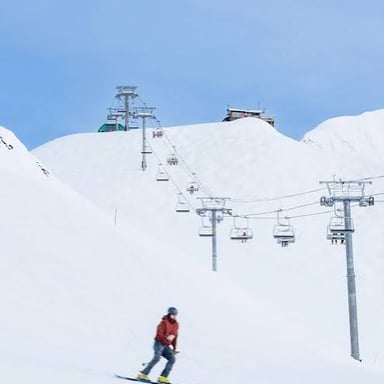 Skiers descending a snowy mountain slope.