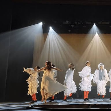 Performers on a lit theater stage in front of an audience.