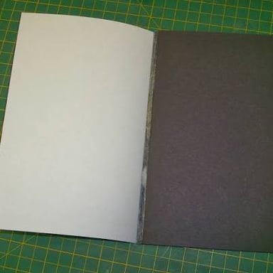 A person applying glue to attach two pieces of paper.