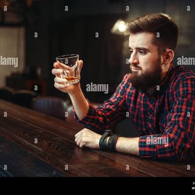 A person seated at a bar with a drink.