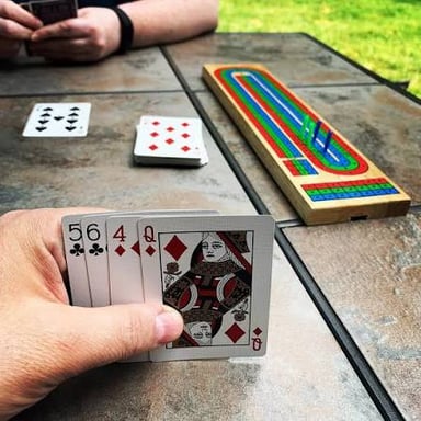 A hand of cards being distributed to players at a table.