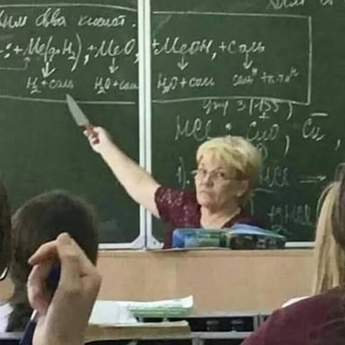 A teacher writing on a classroom chalkboard