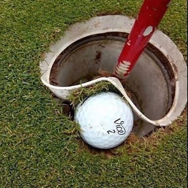 A golf ball rests close to the cup, ready for a short tap-in putt.