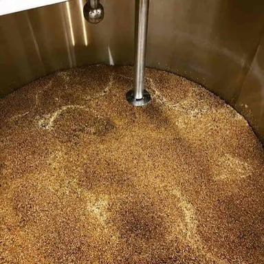A brewer stirring a mash of crushed grain in a mash tun