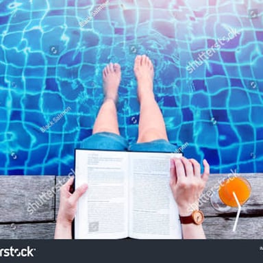 A reader relaxing beside a swimming pool with a book.