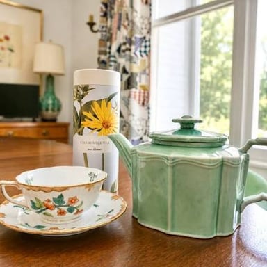 A cup of herbal infusion with chamomile flowers and mint leaves nearby.
