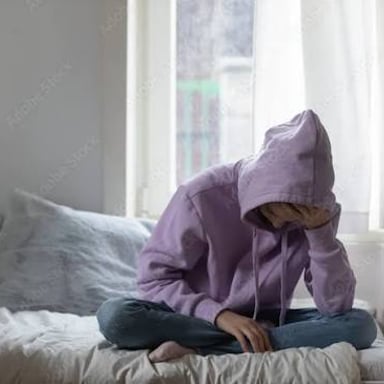 A teenager sitting alone and appearing dejected