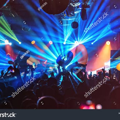 A crowd dancing at a rave with a DJ performing.