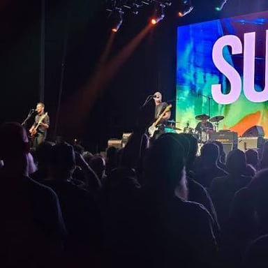 A rock band performing onstage in a concert setting.