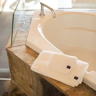 A bath towel folded beside a bathtub.