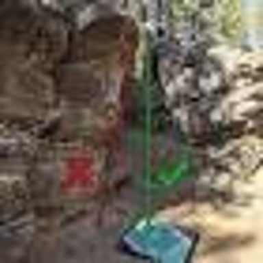 A thick folding crash pad lies below a low outdoor bouldering route.
