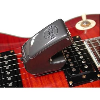 A handheld EBow positioned above the strings of an electric guitar