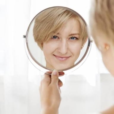 A person looking thoughtfully at their reflection.