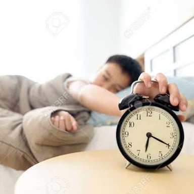 An alarm clock sounds beside a bed, interrupting sleep.