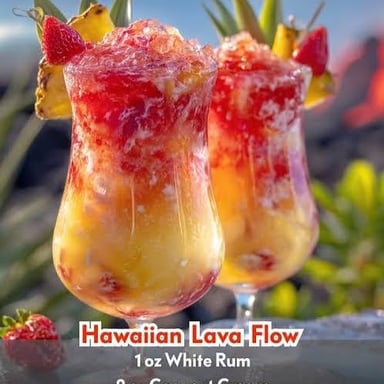 A layered tropical cocktail with red strawberry puree swirling through a creamy pale base