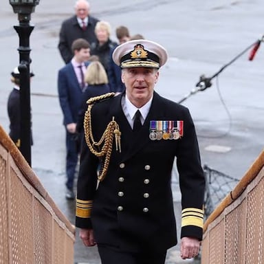 A senior naval officer in uniform aboard a ship.