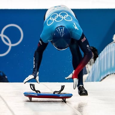 An athlete riding a skeleton sled headfirst down an icy track.